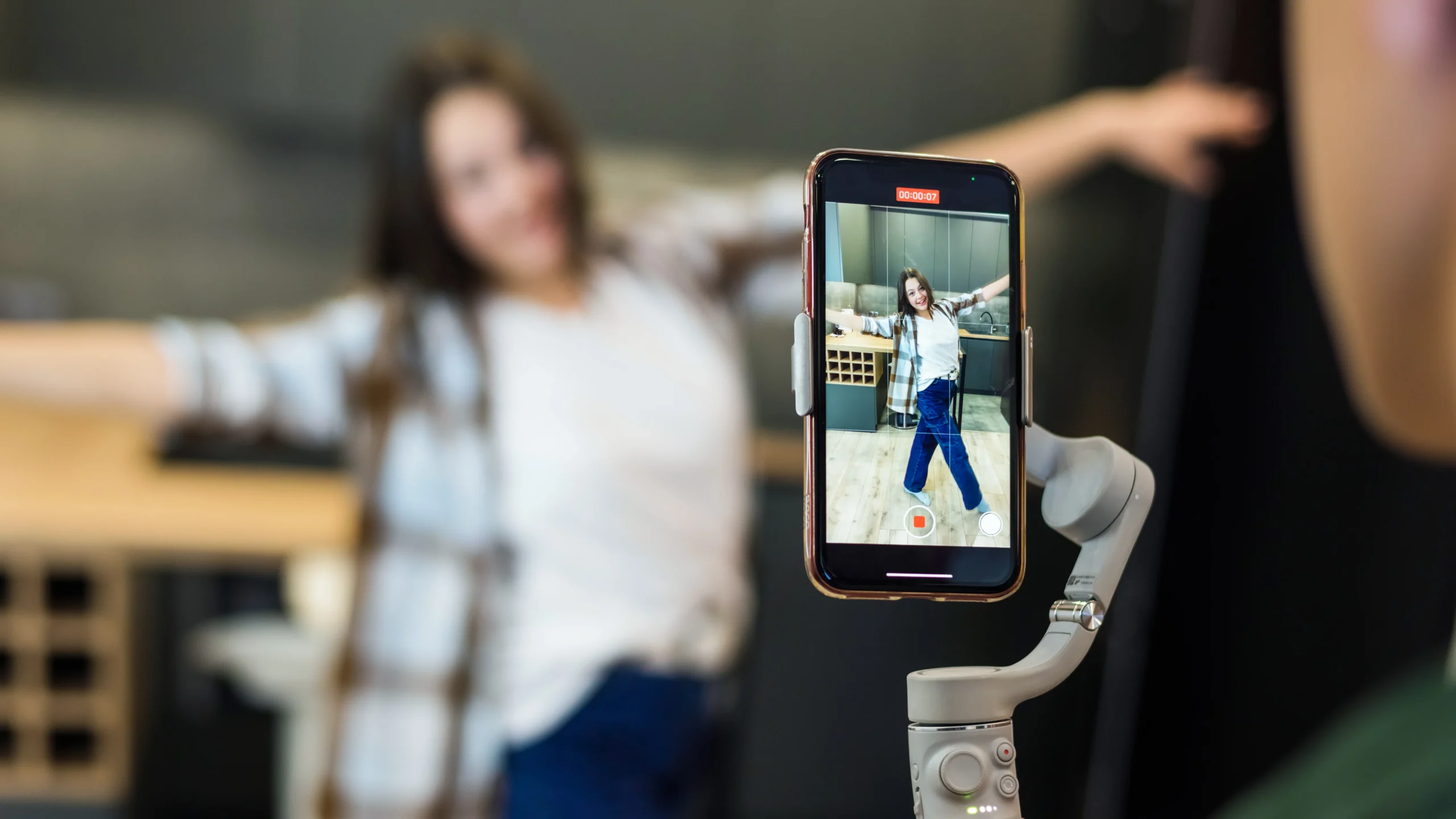 Funcionário pode ser obrigado a gravar vídeos para a empresa? Mulher grava conteúdo com celular em ambiente corporativo.